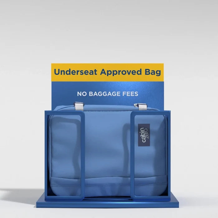 A blue Underseat Approved Bag with a small black brand patch, displayed inside a blue stand with a yellow and blue sign that reads 'Underseat Approved Bag' and 'NO BAGGAGE FEES'.
