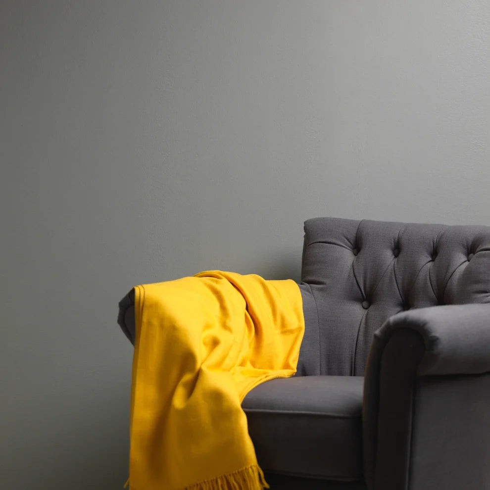 Frenchic City Slicker grey wall behind a grey armchair with a yellow throw
