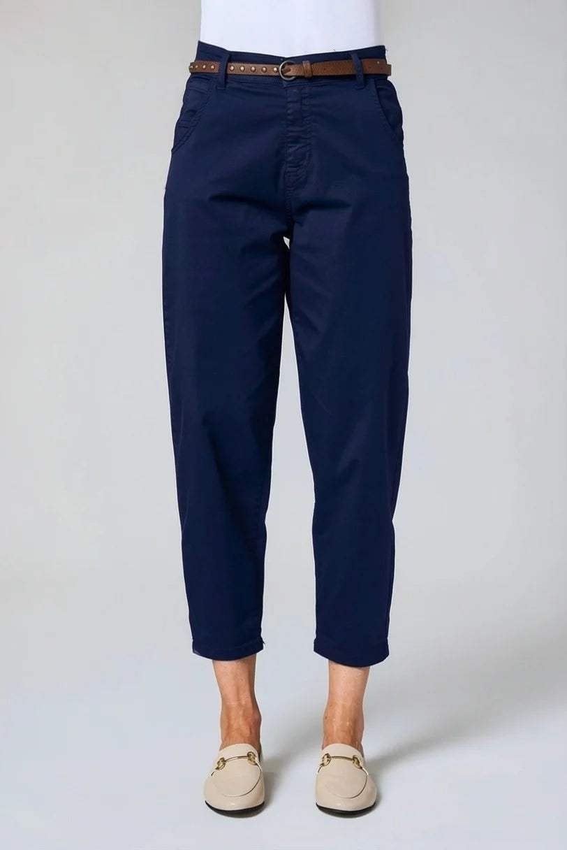 A person wearing navy blue cropped pants with a brown belt, paired with a white top and beige loafers, shown from the waist down against a light gray studio background by Weirs Gifts