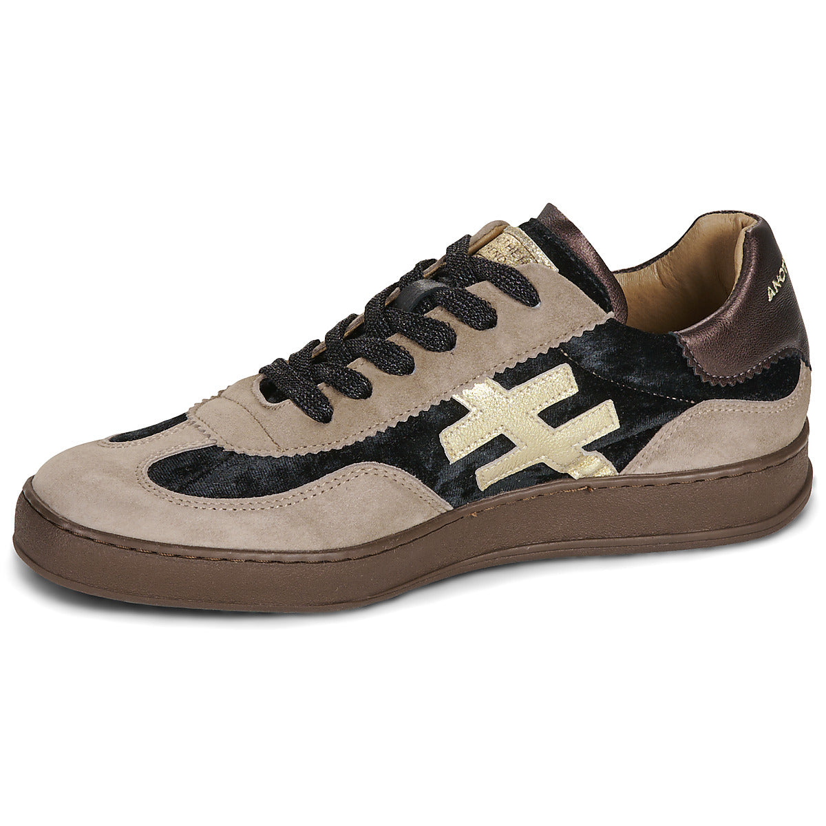 A low-top sneaker featuring beige suede and black velvet panels, black laces, a brown sole, and a large metallic gold cross logo on the side at Weirs Gifts