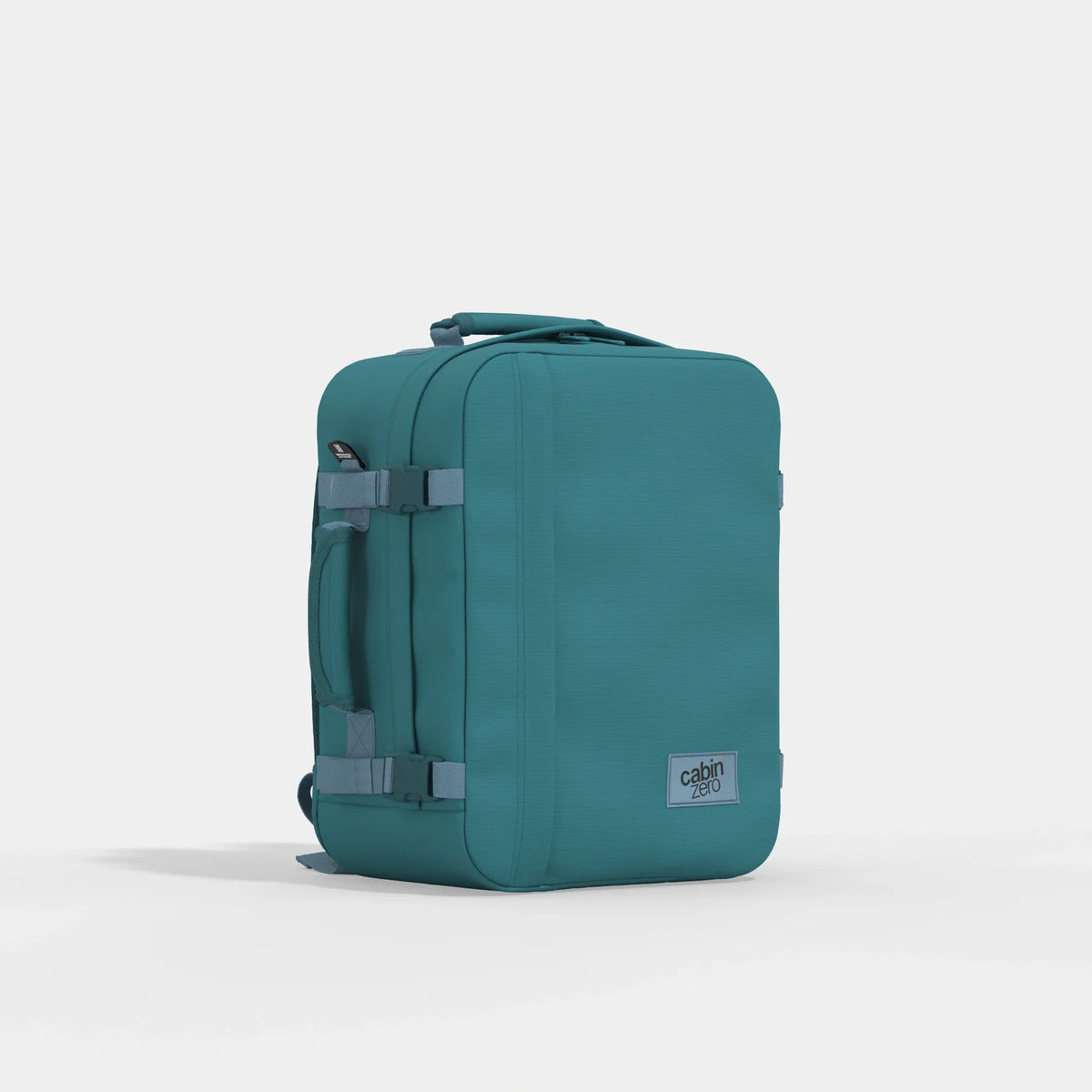 A teal soft-sided rolling suitcase with gray straps and a small gray 'cabin' brand patch on the lower right, photographed on a clean light gray studio background.