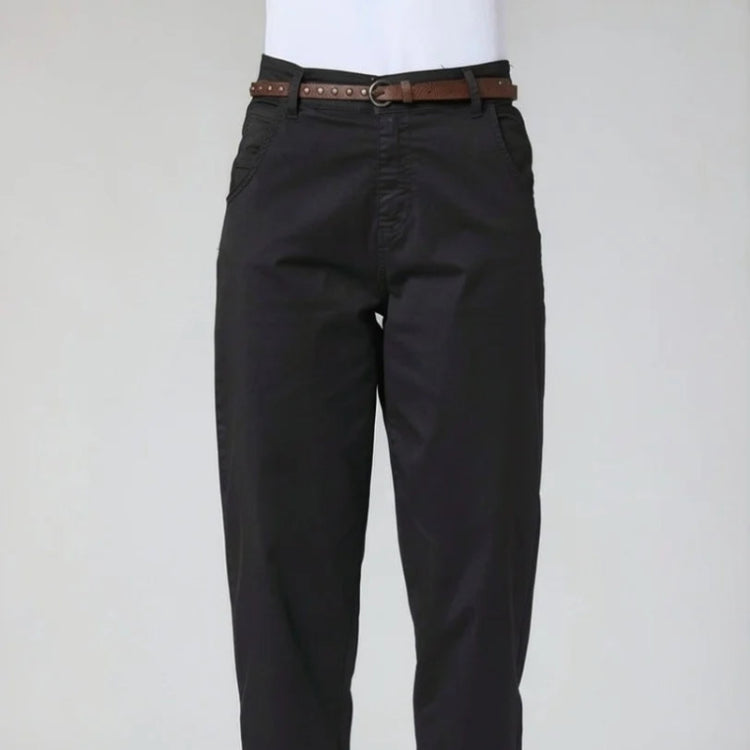 A person wearing black cropped pants with a brown belt, paired with a white top and beige loafers, shown from the waist down against a light gray studio background at Weirs GIfts