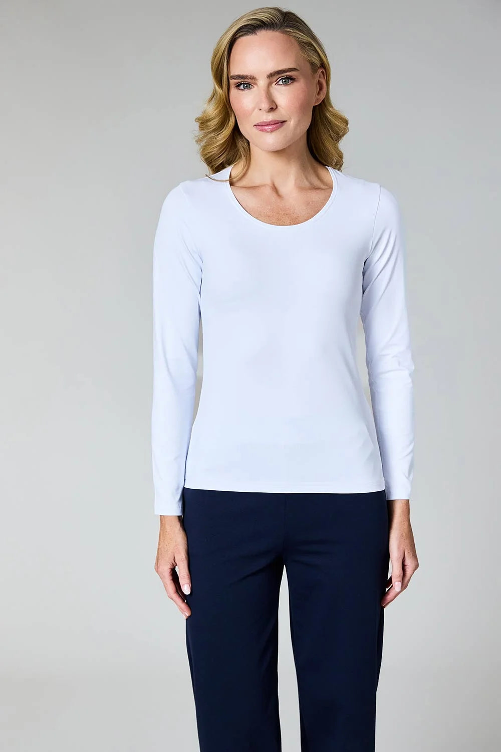 A woman modeling a light blue long-sleeve crewneck top paired with dark navy pants, photographed against a neutral light gray studio background by Weirs Gifts