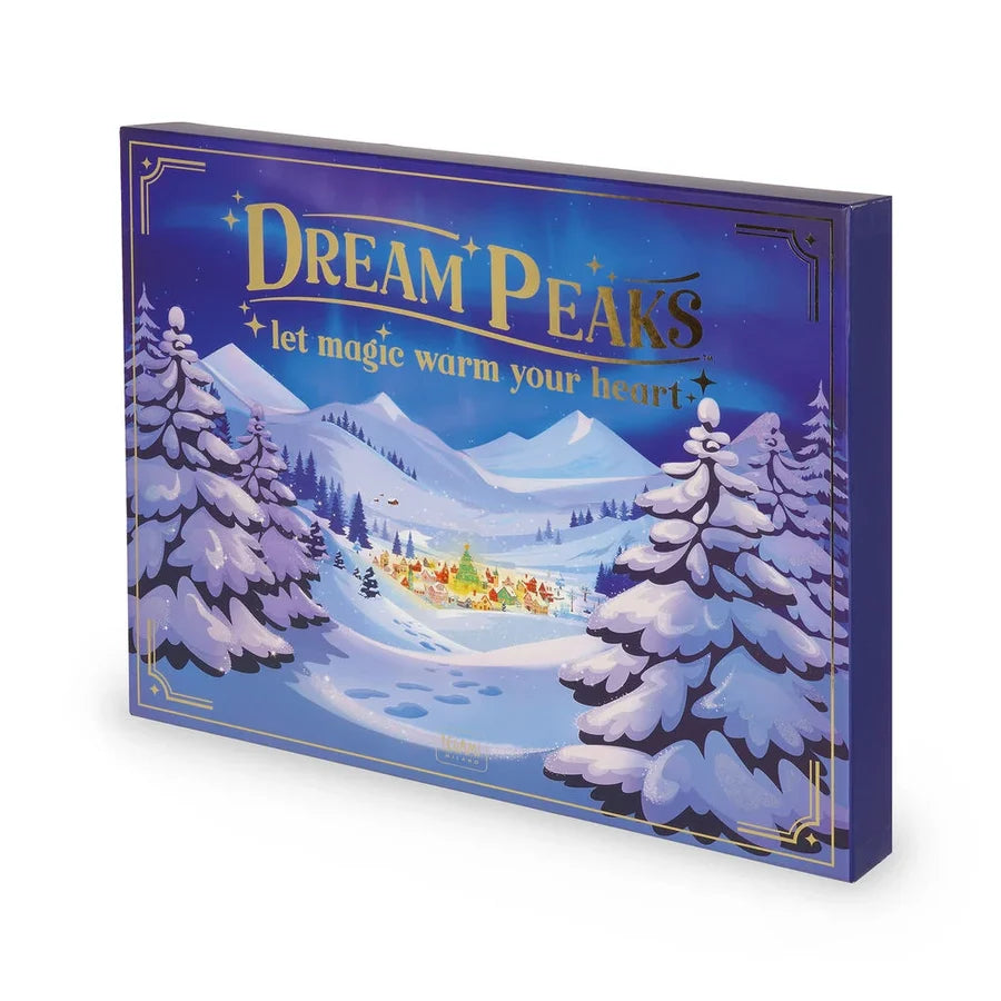 A boxed product featuring the 'Dream Peaks' winter scene artwork, with snow-covered mountains, pine trees, and a small village under a blue night sky. The box is shown at an angle on a clean white background at Weirs Gifts.