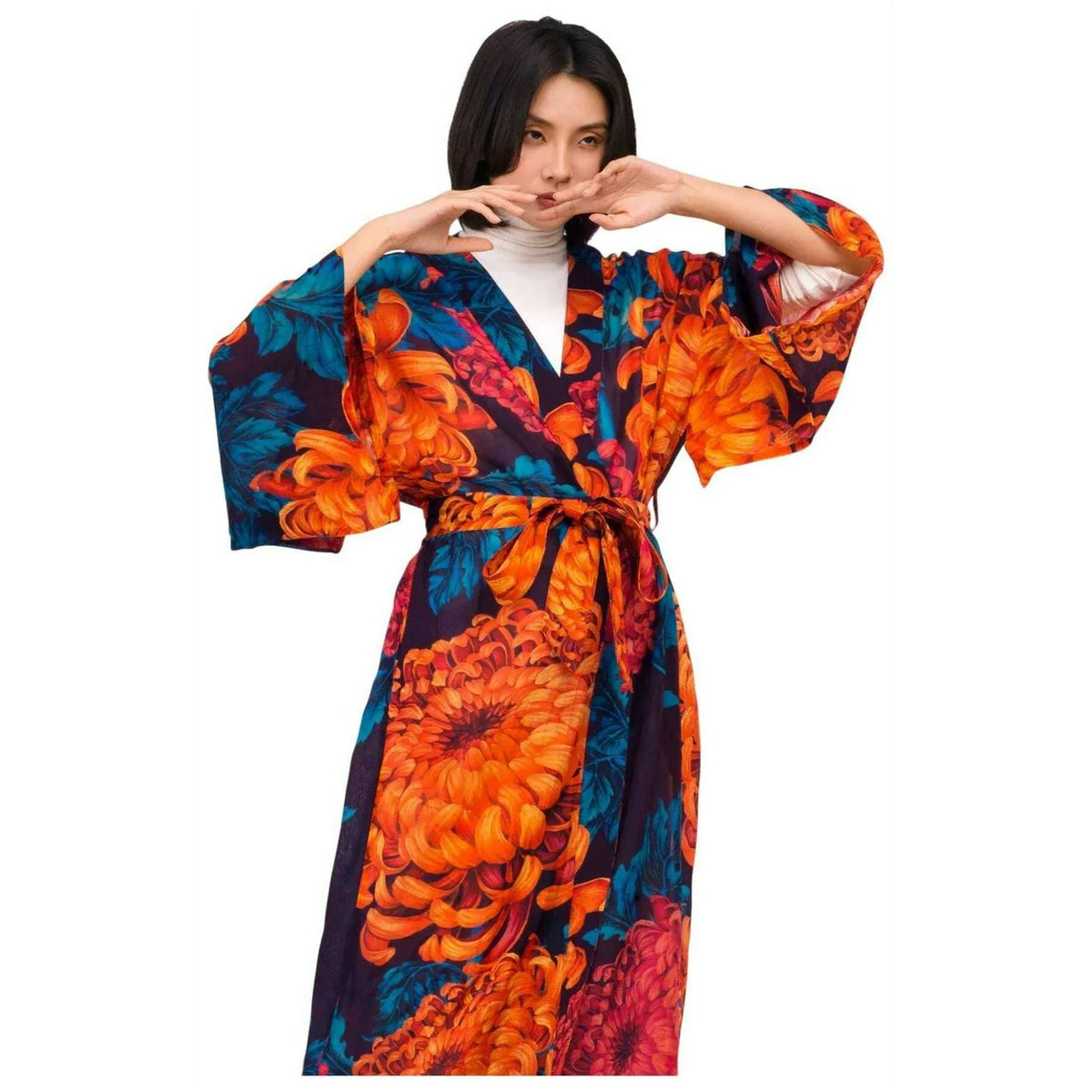 A woman modeling a kimono-style robe with a bold floral print in orange, blue, and dark purple, styled over a white top against a plain white background by Weirs Gifts