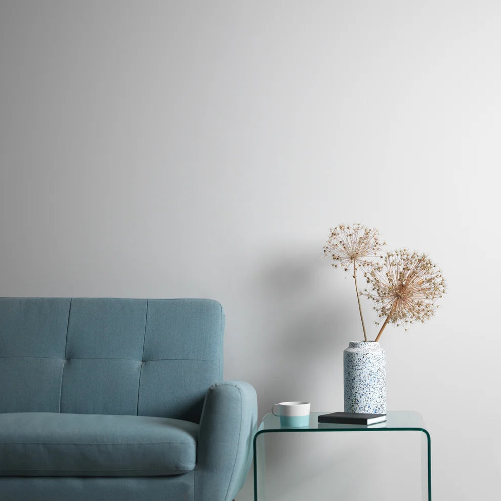 Frenchic Whistle pale grey wall behind a blue sofa and glass side table